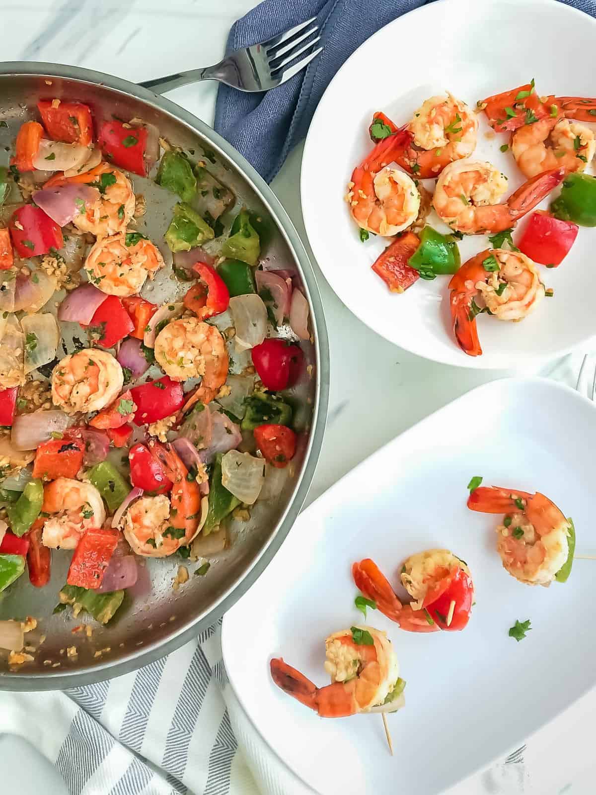 pan-fried prawns and peppers in a stainless steel pan and served on a plate and on toothpicks.