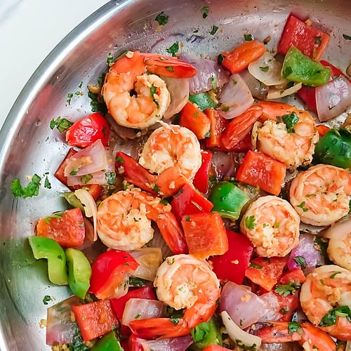 pan fried prawns and peppers in a stainless steel pan.