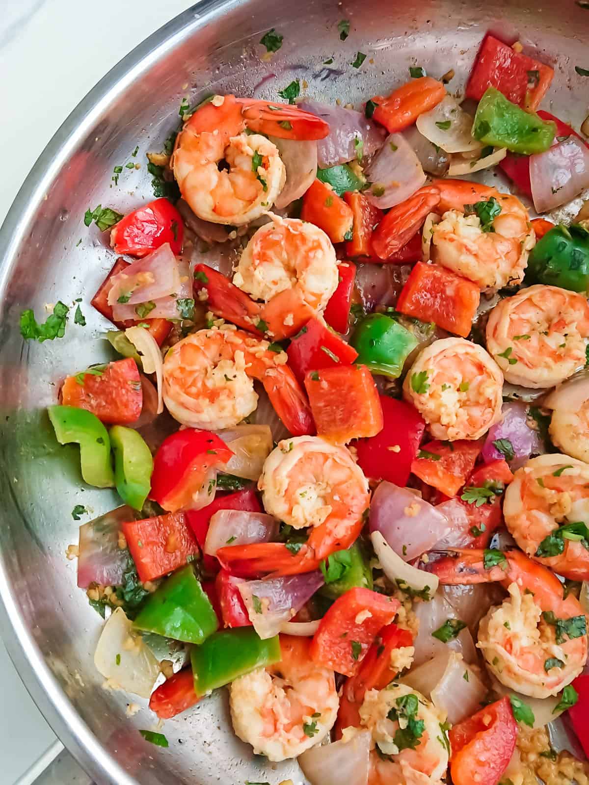 pan fried prawns and peppers in a stainless steel pan.