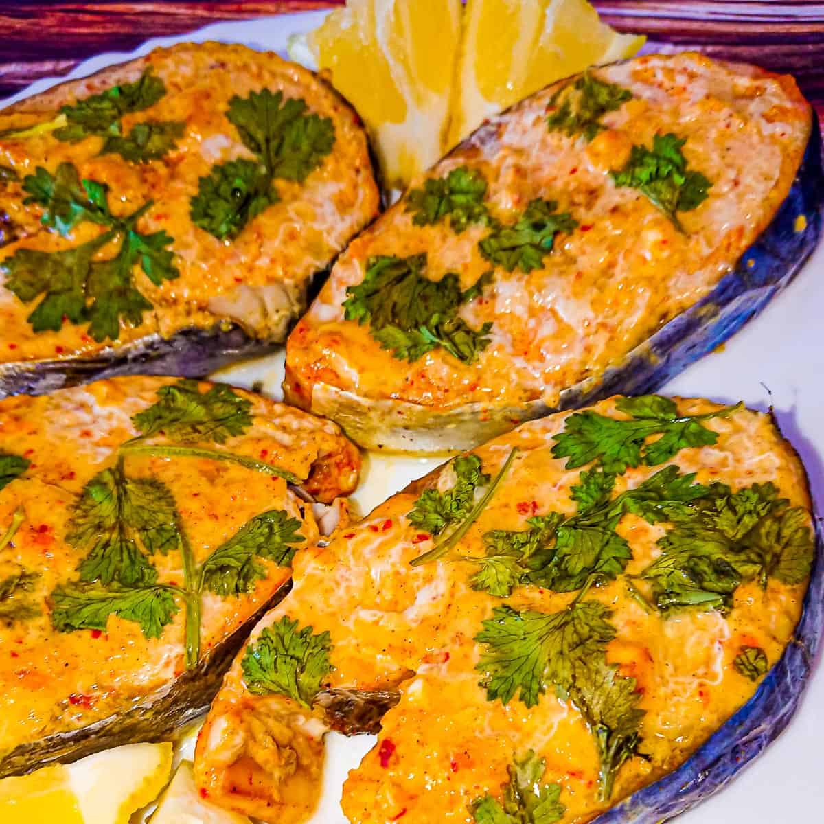 4 baked fish steaks on a white plate.