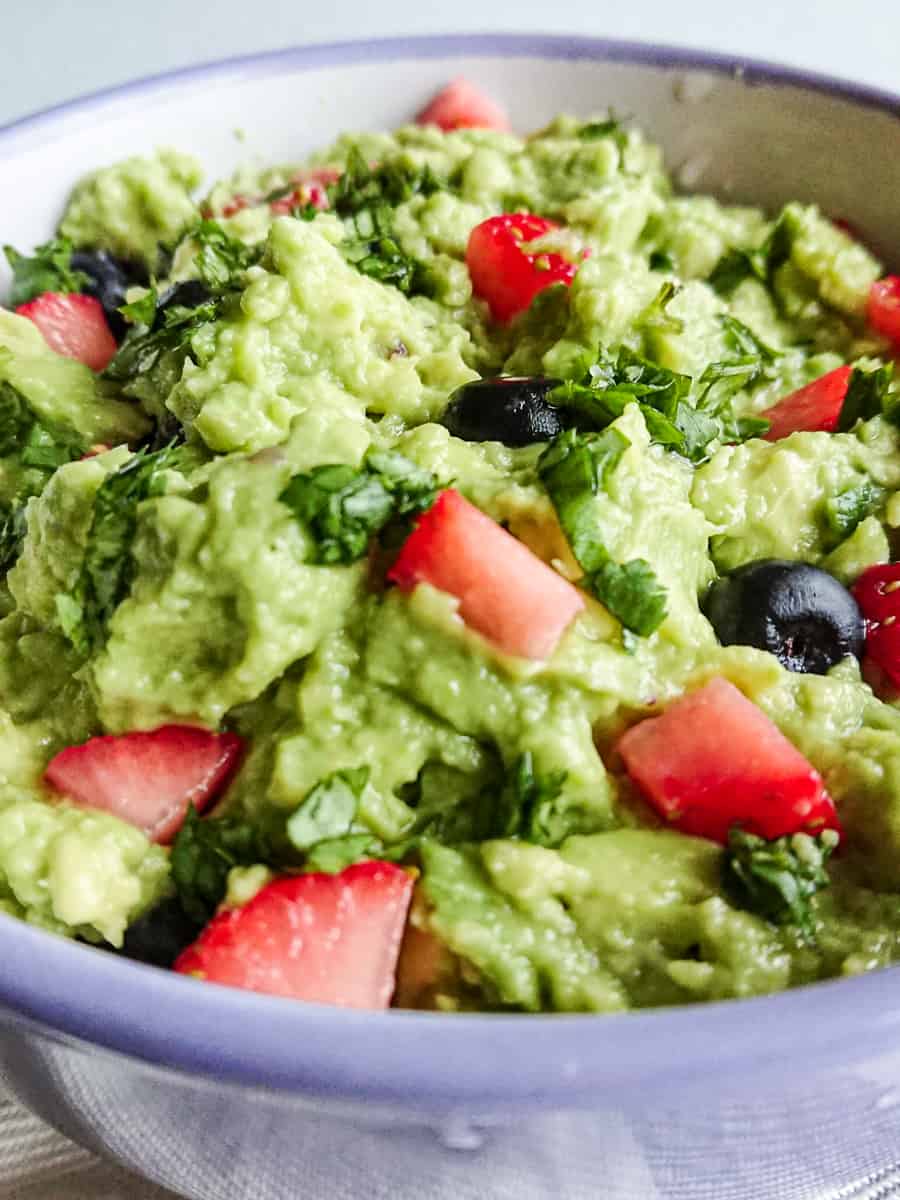 close up view of no onion guacamole in a white bowl.