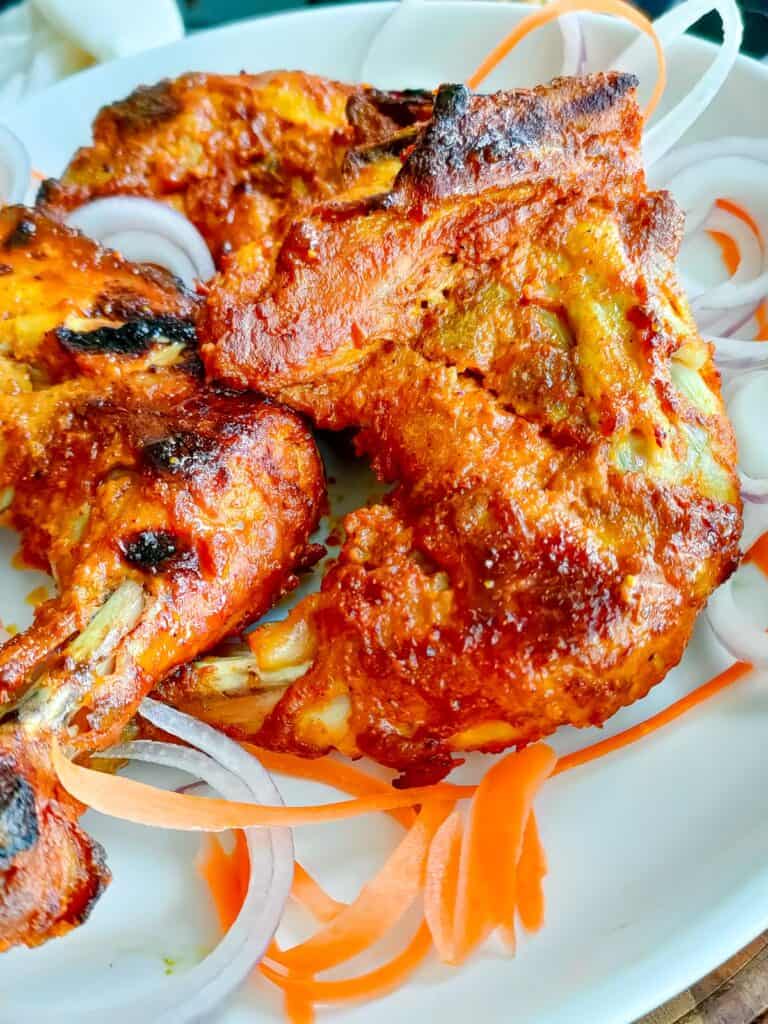 closeup view of tandoori roast chicken legs on a white plate.