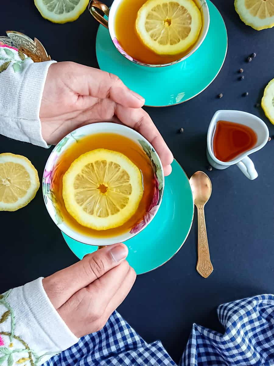lemon ginger turmeric shots in 2 cups with slices of lemon.
