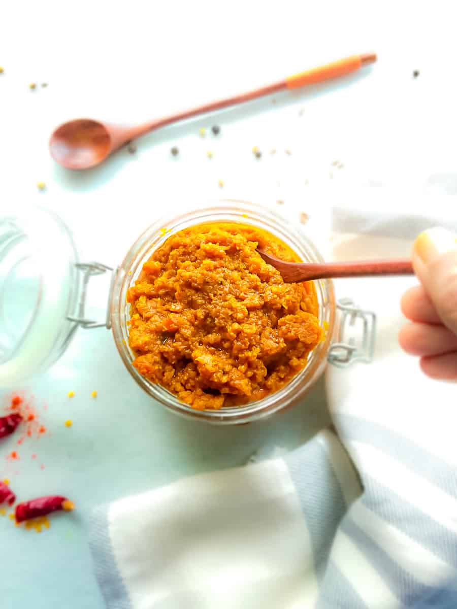 Homemade Indian curry paste in a glass jar with a wooden spoon in it.