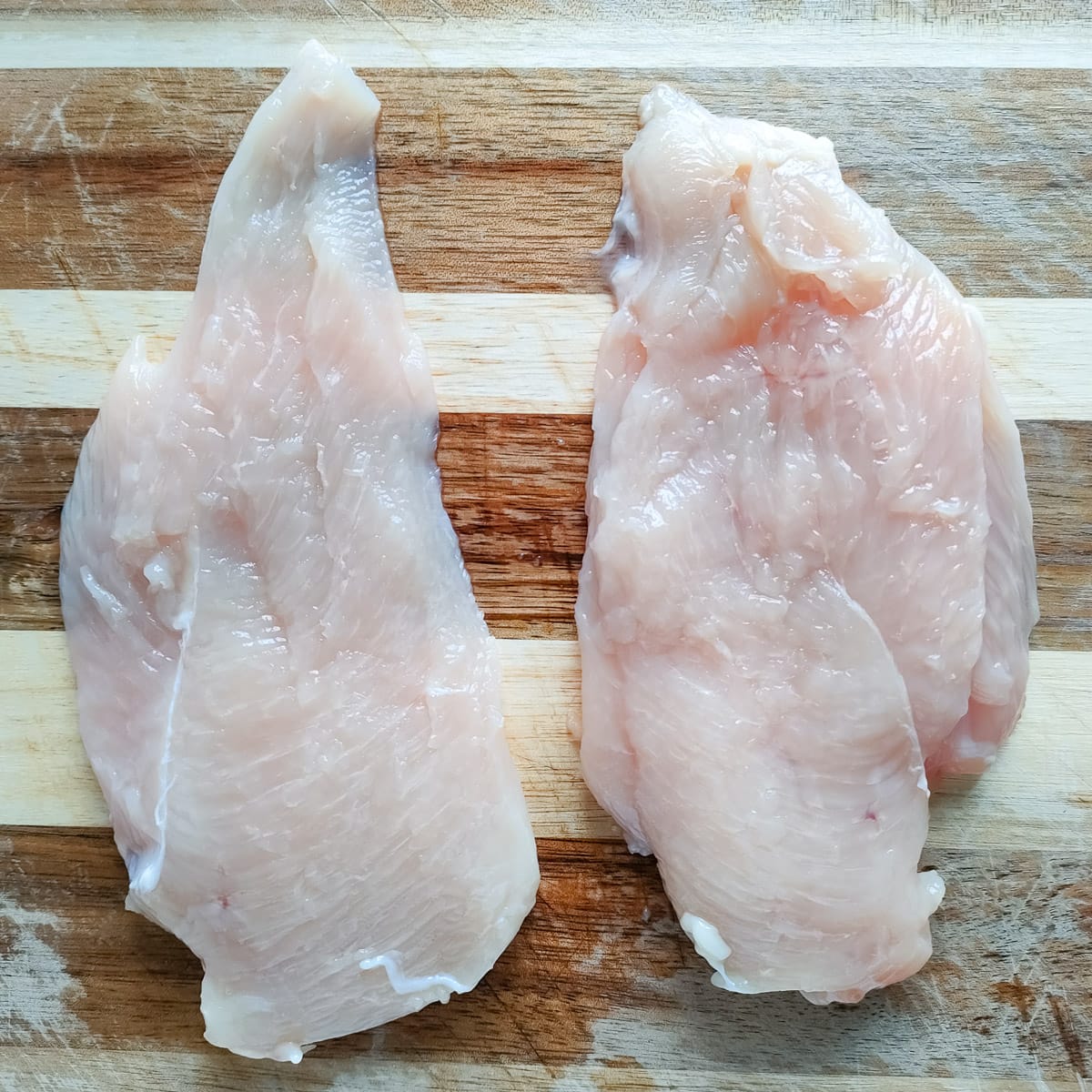 thinly sliced chicken breast on a chopping board.