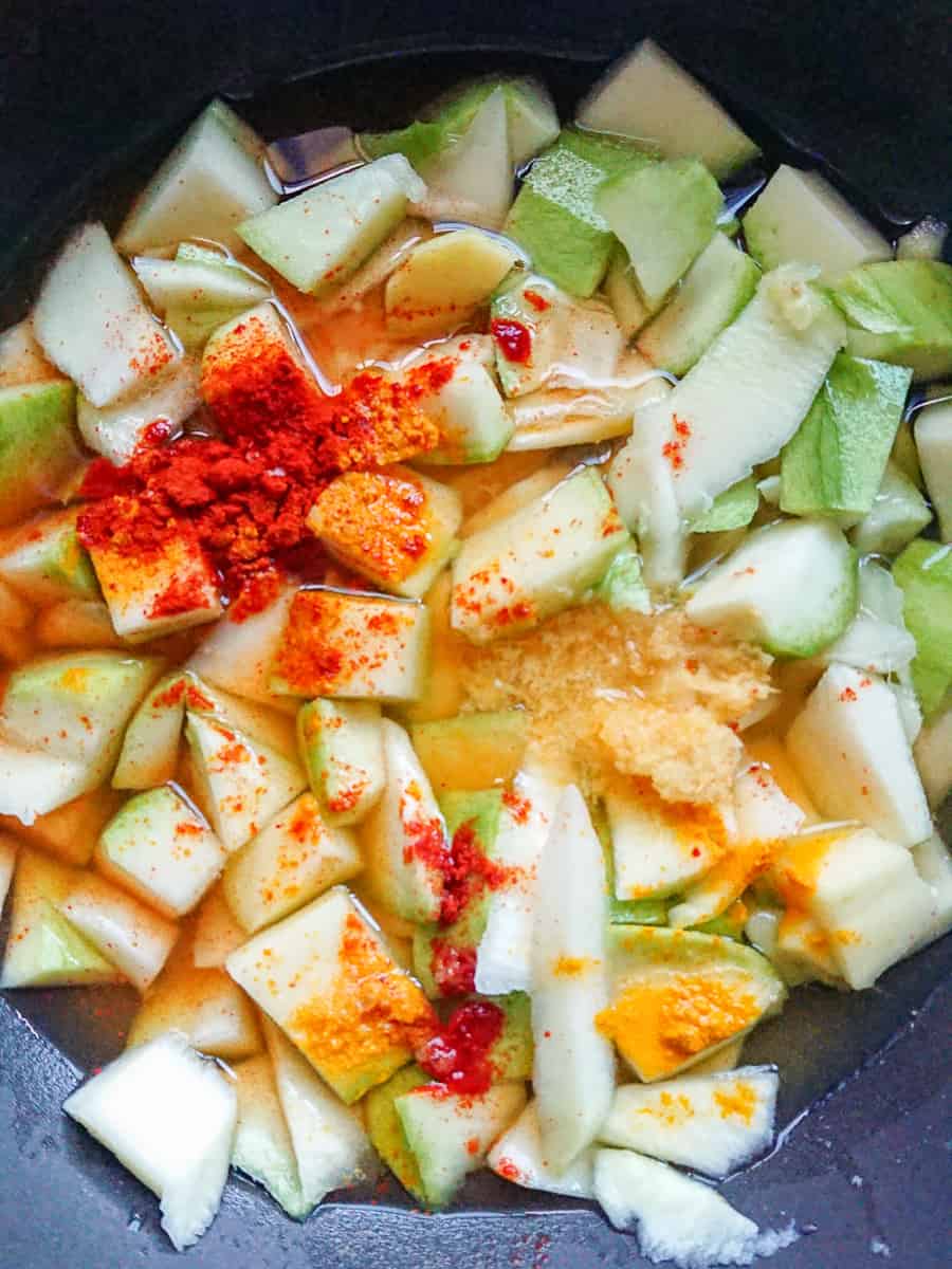 diced green mangoes being cooked with spices in a pan