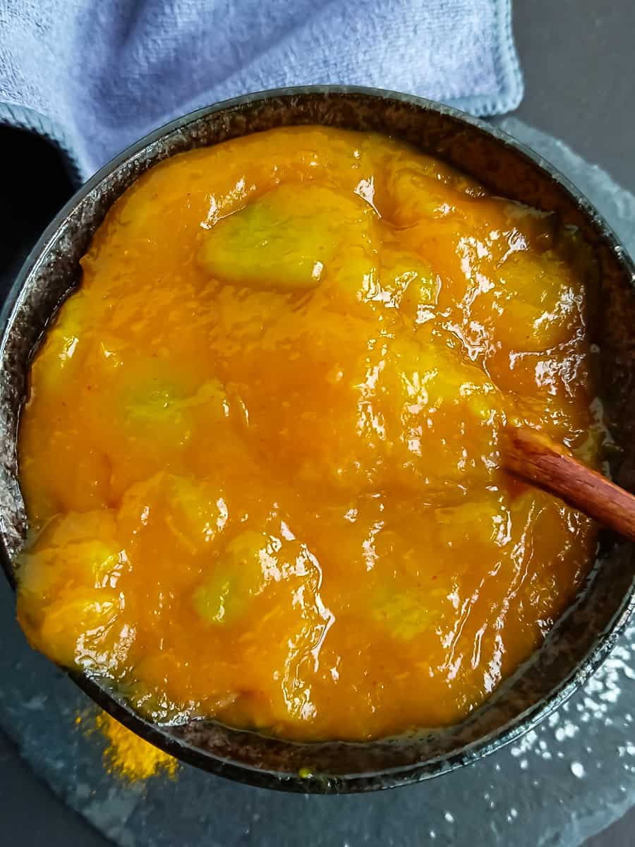 Close-up view of homemade raw mango chutney in a black ceramic bowl.