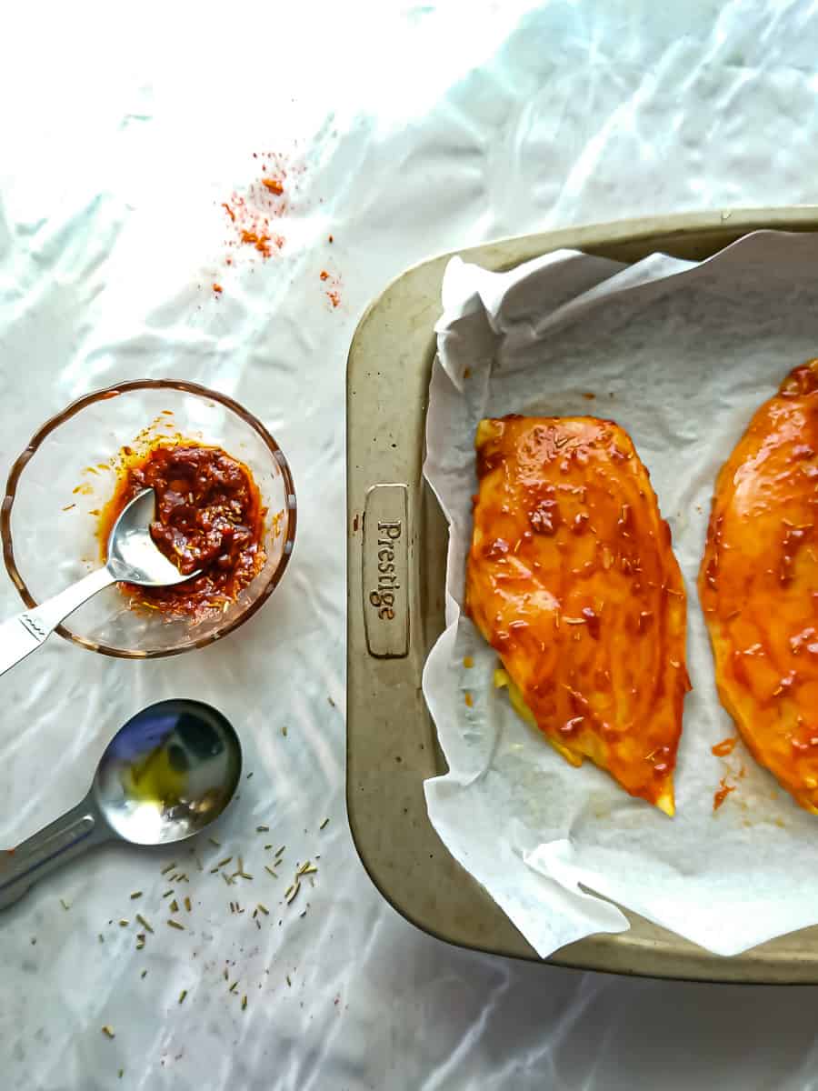 Marinated chicken breasts placed in a baking tray.