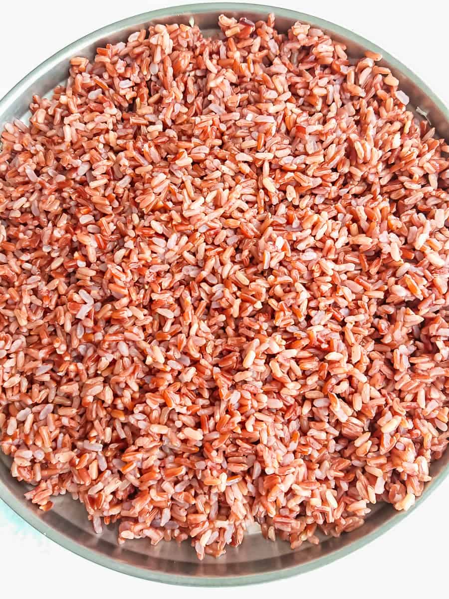 cooked red rice spread out in a plate.