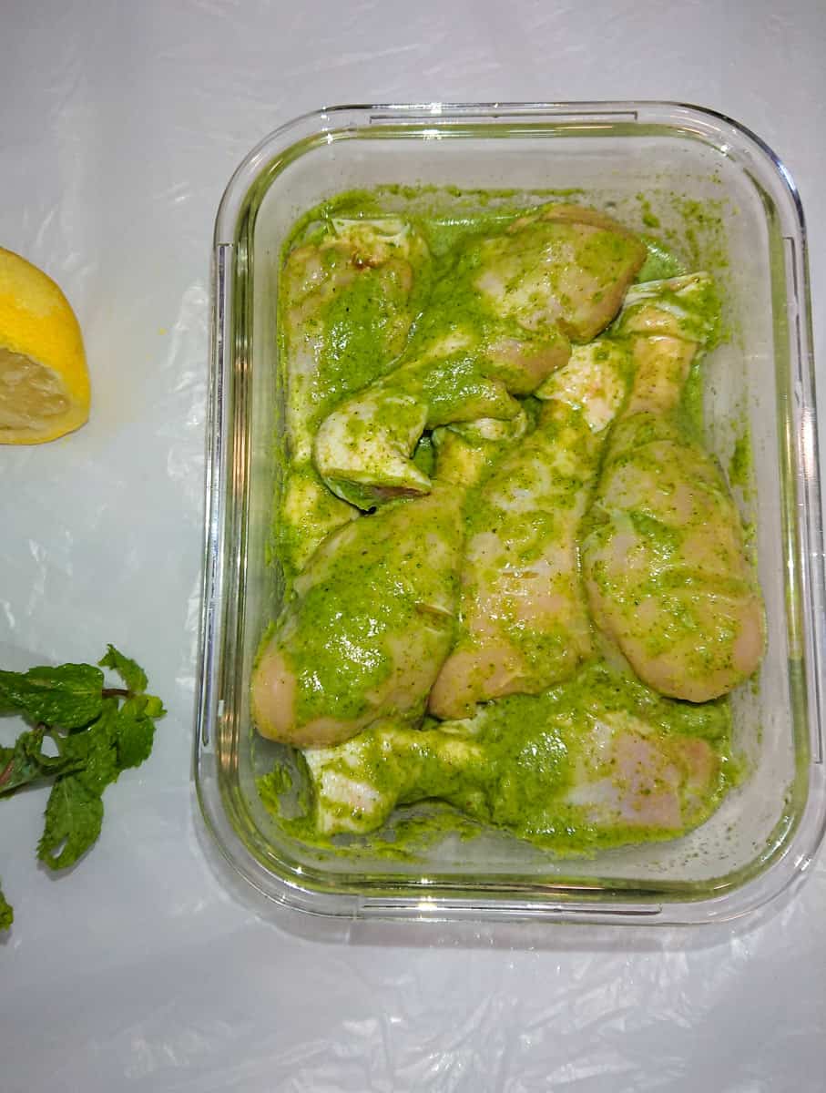 Easy Baked Pudina Chicken (Hariyali Chicken) marinated chicken drumsticks in a glass container