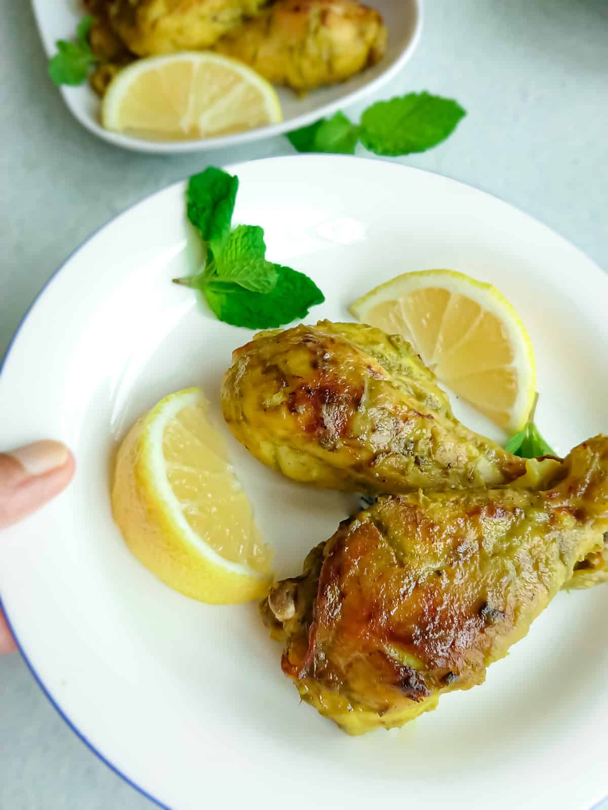 easy oven baked hariyali chicken legs served on a white plate with lemon slices.