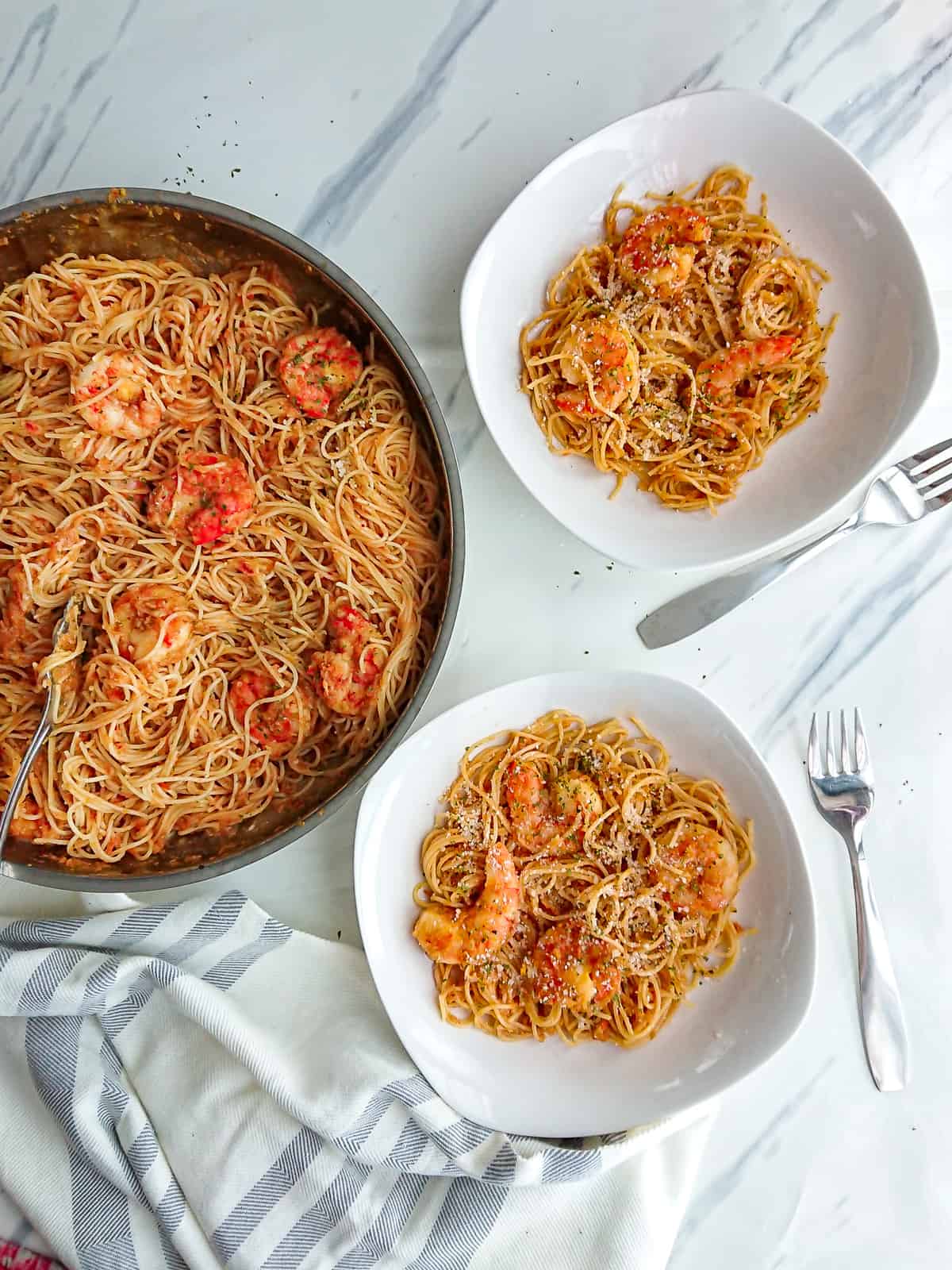 chilli and garlic prawn pasta served from a pan on 2 white plates.