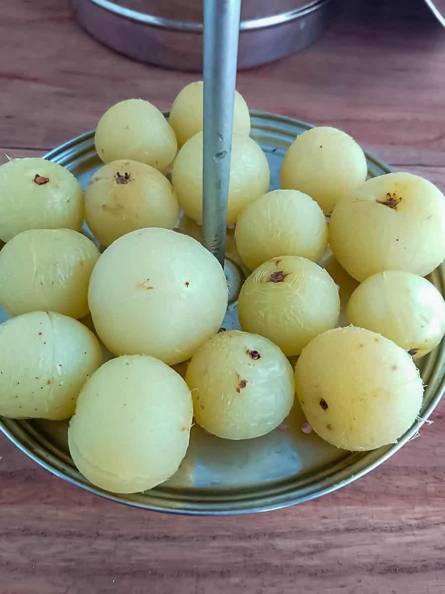 steamed gooseberries for gooseberry pickle in a steamer plate.