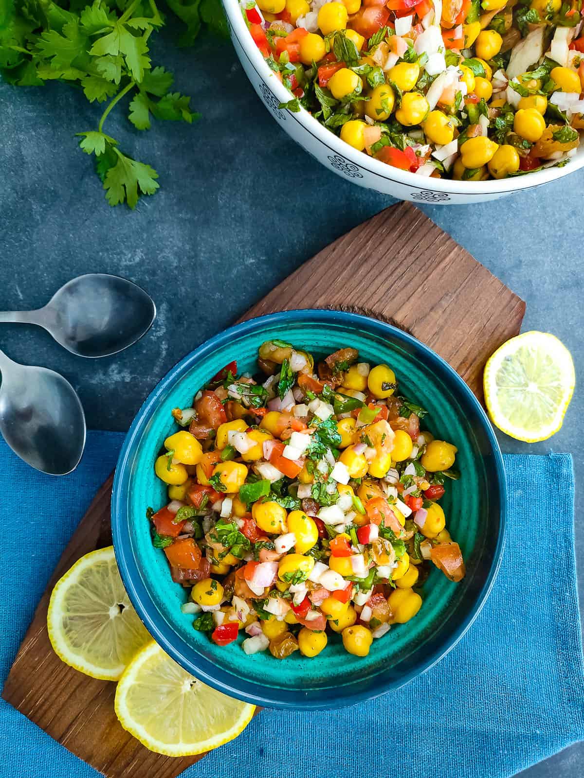 Chole chaat salad in a blue bowl and a white salad bowl next to it.