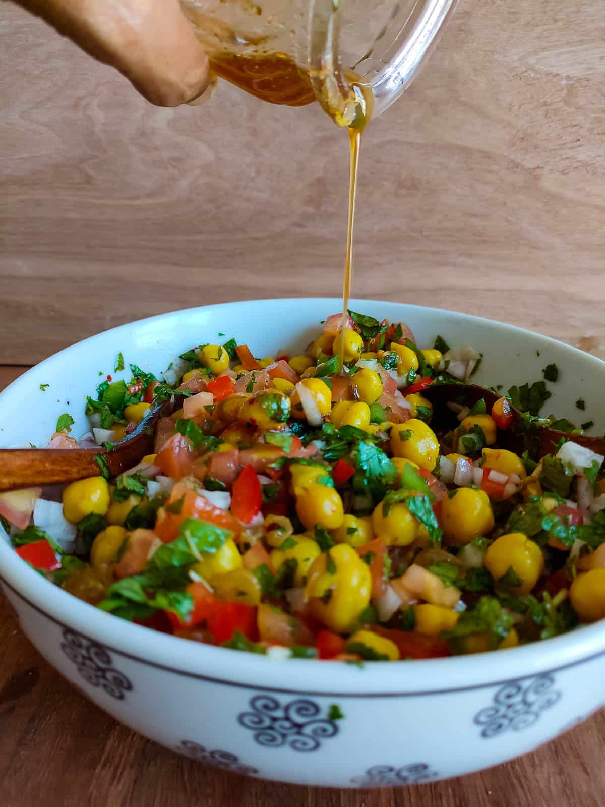 Indian salad dressing being drizzled on kabuli chana salad.