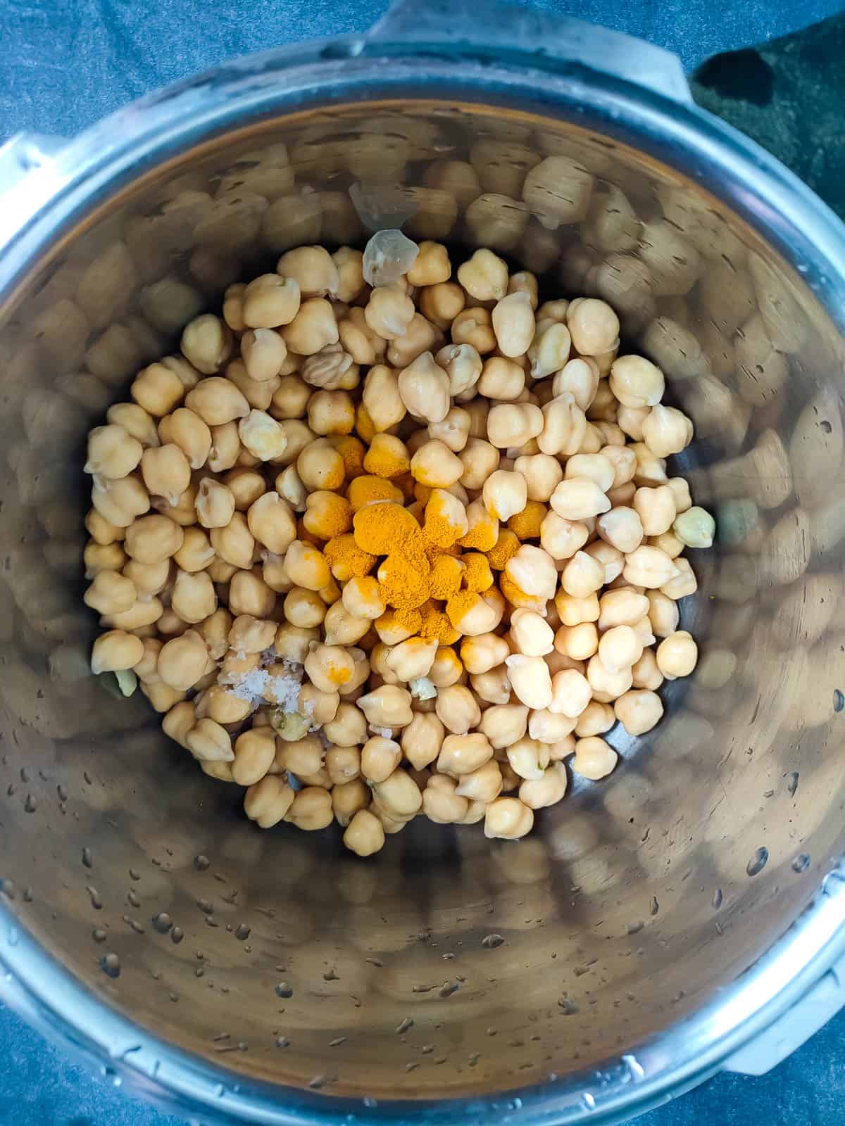 Soaked chickpeas being cooked with turmeric and salt.