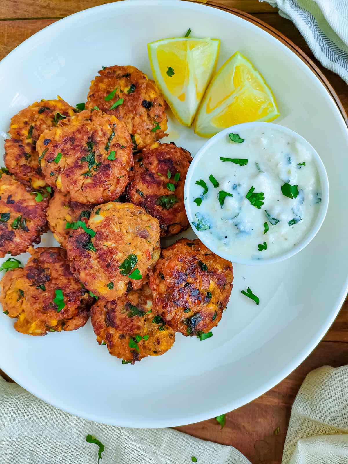 Indian fish cakes without potato on a white ceramic plate with a bowl of yogurt dip.