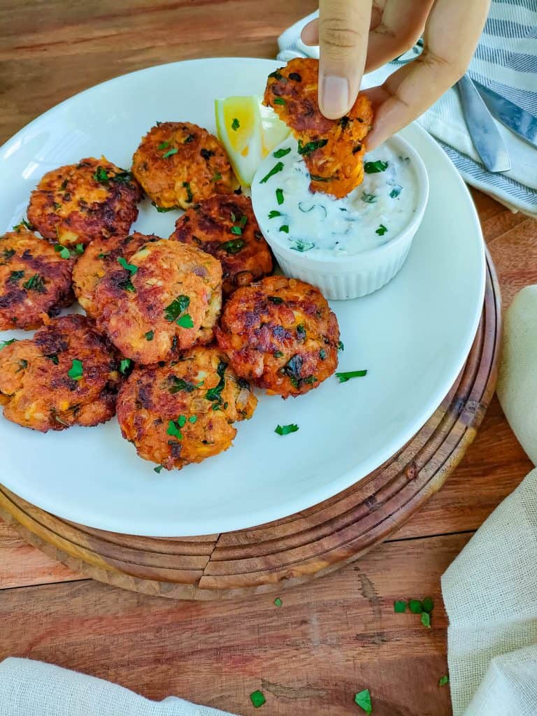 Mackerel fish cakes in a white ceramic plate with a bowl of yogurt dip.