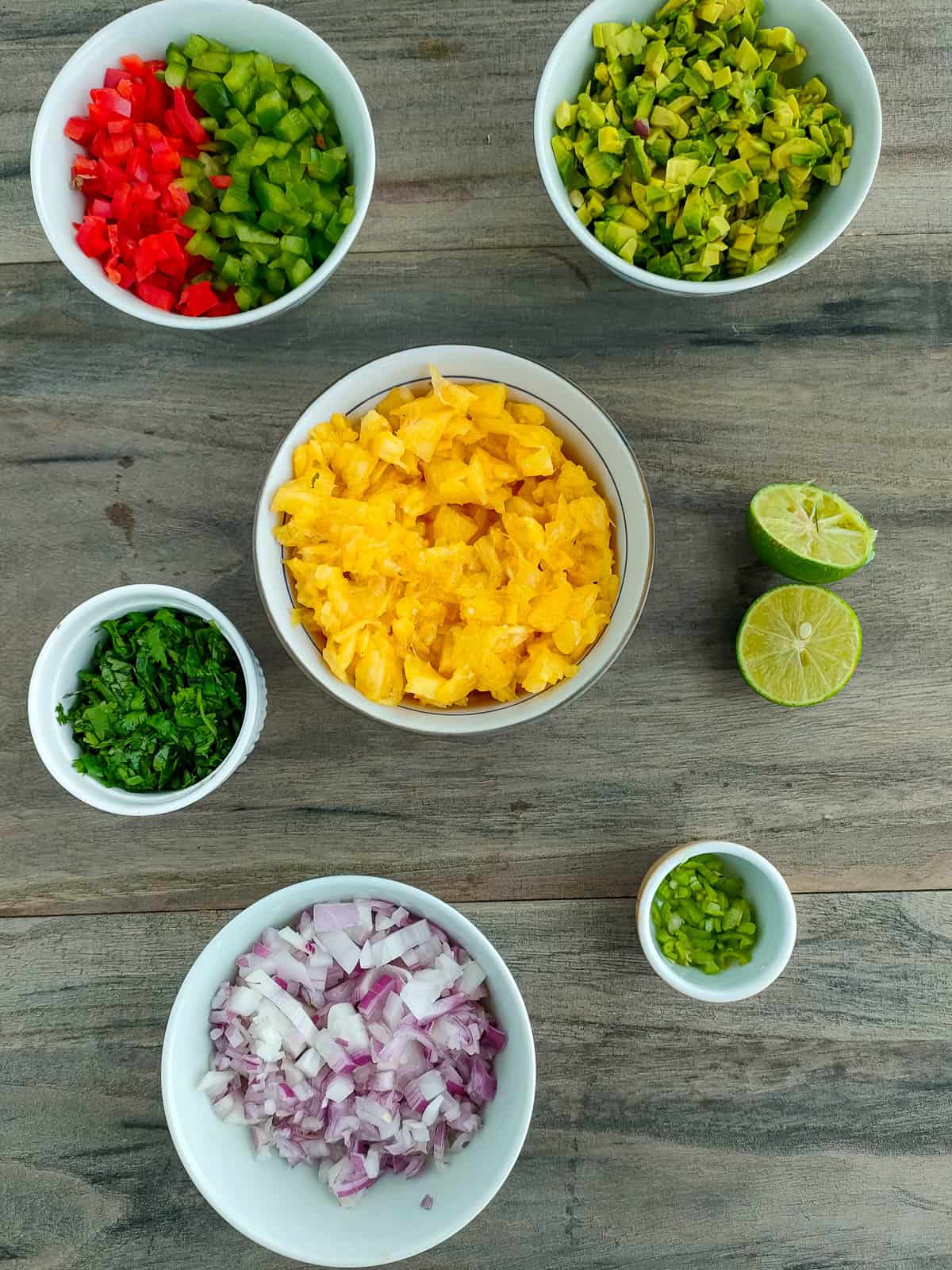 chopped ingredients for pineapple avocado salsa in separate bowls.