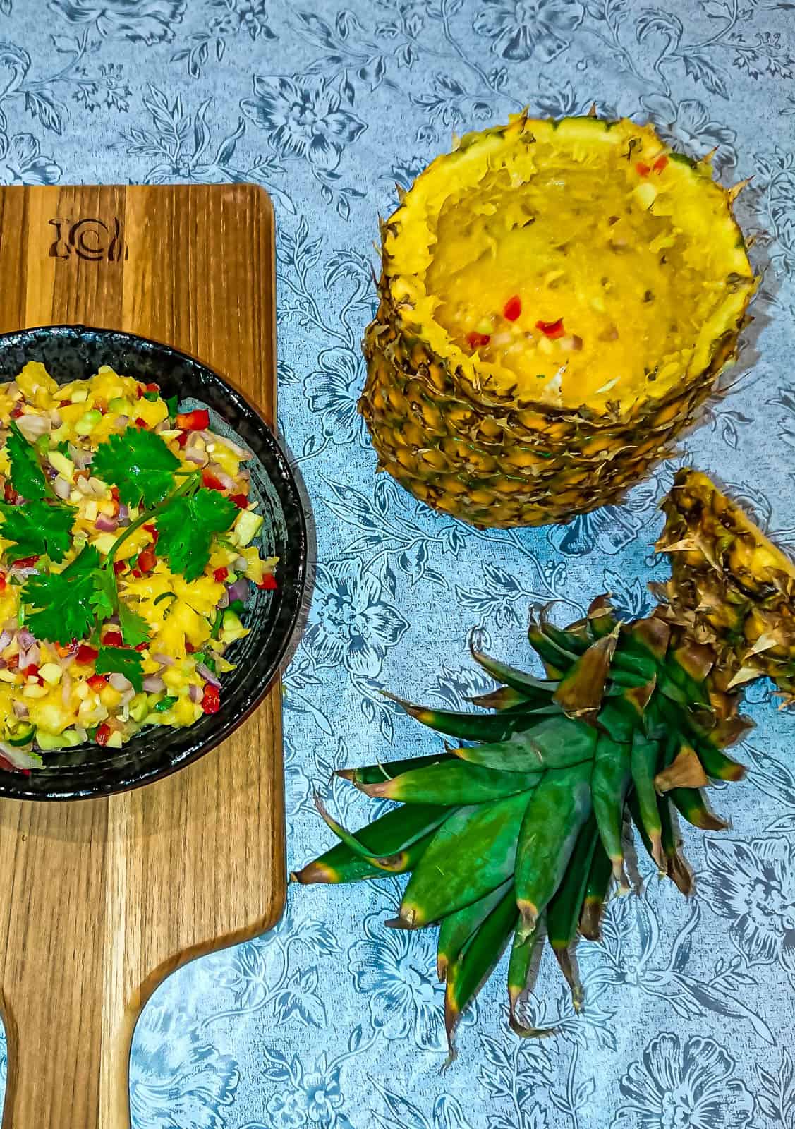 pineapple avocado salsa in a black bowl and a pineapple "bowl" with the top cut off..