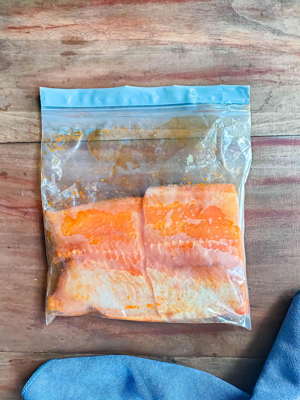 Fish fillets seasoned with salt, oil and chili powder in a ziplock bag.