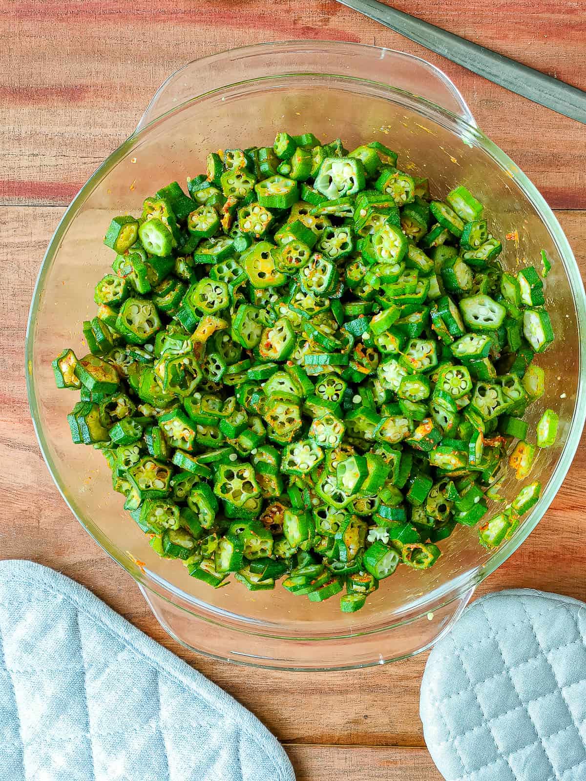 Chopped okra mixed with spices in a glass bowl.