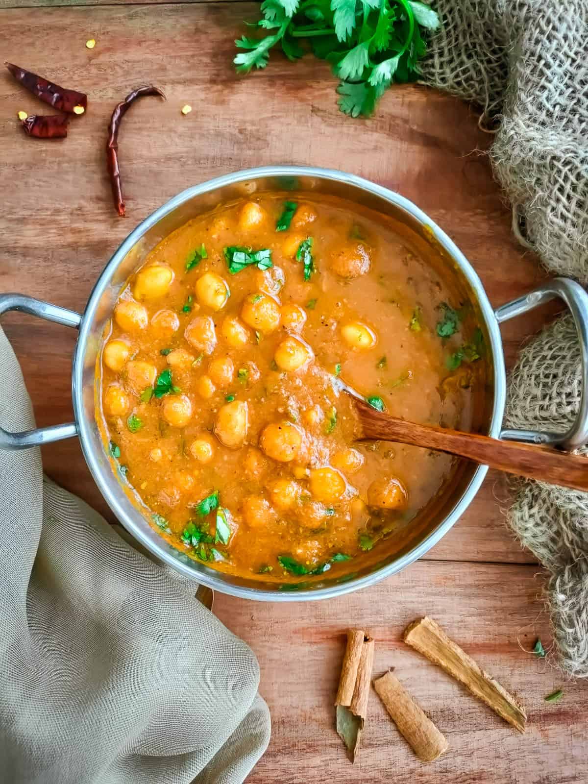 South Indian chana masala in a metal serving bowl with a ladle in it.