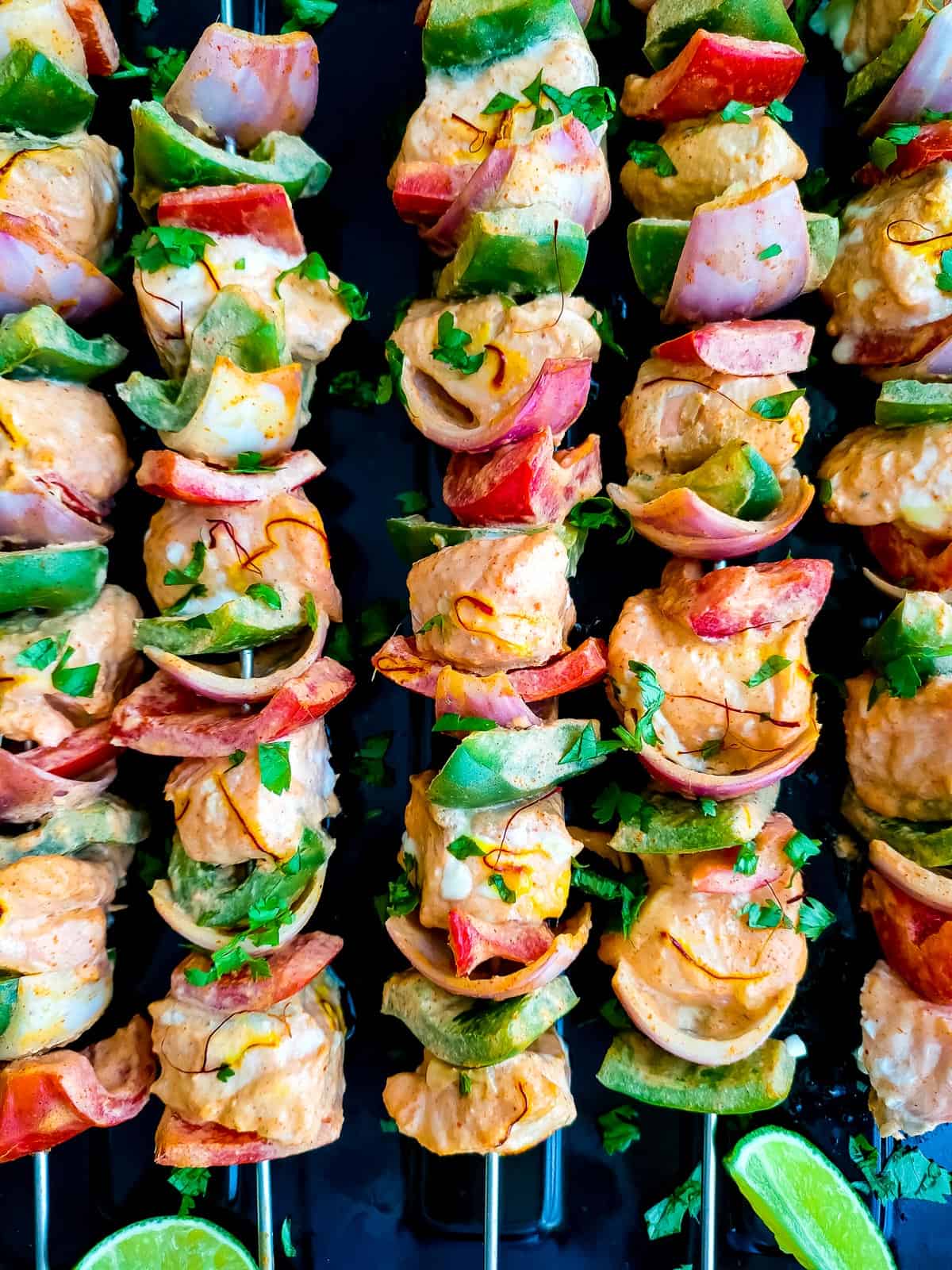 Close-up view of baked salmon bites with onions and peppers on a black tray.