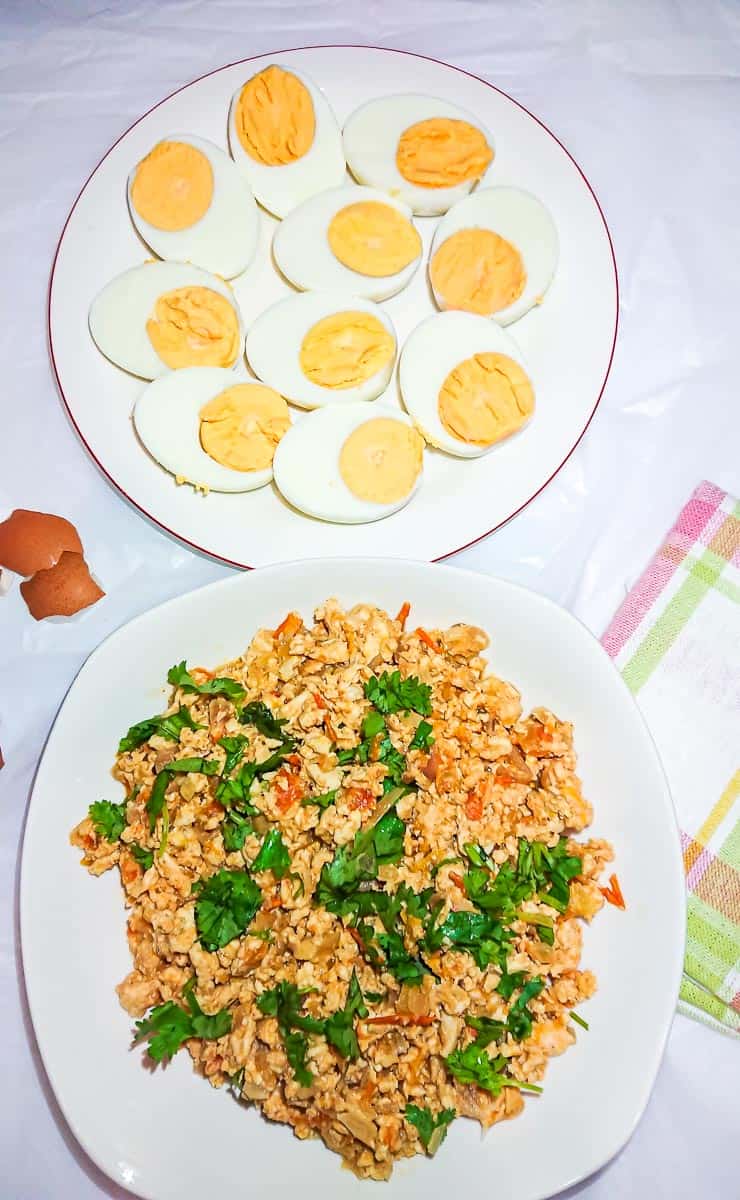 Seasoned minced chicken on a white plate and boiled egg halves on another plate.