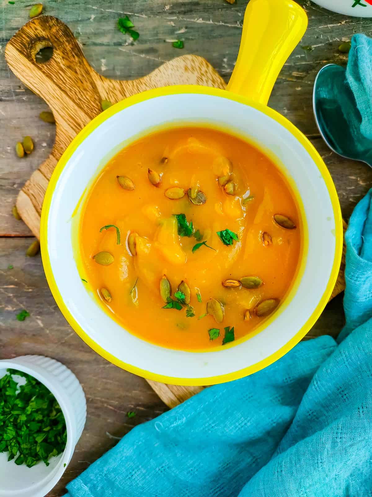 Low carb pumpkin soup without stock in a soup bowl garnished with toasted pumpkin seeds and cilantro.