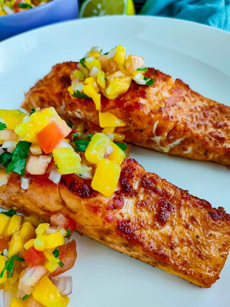 Smoked paprika salmon with mango salsa on a white plate.