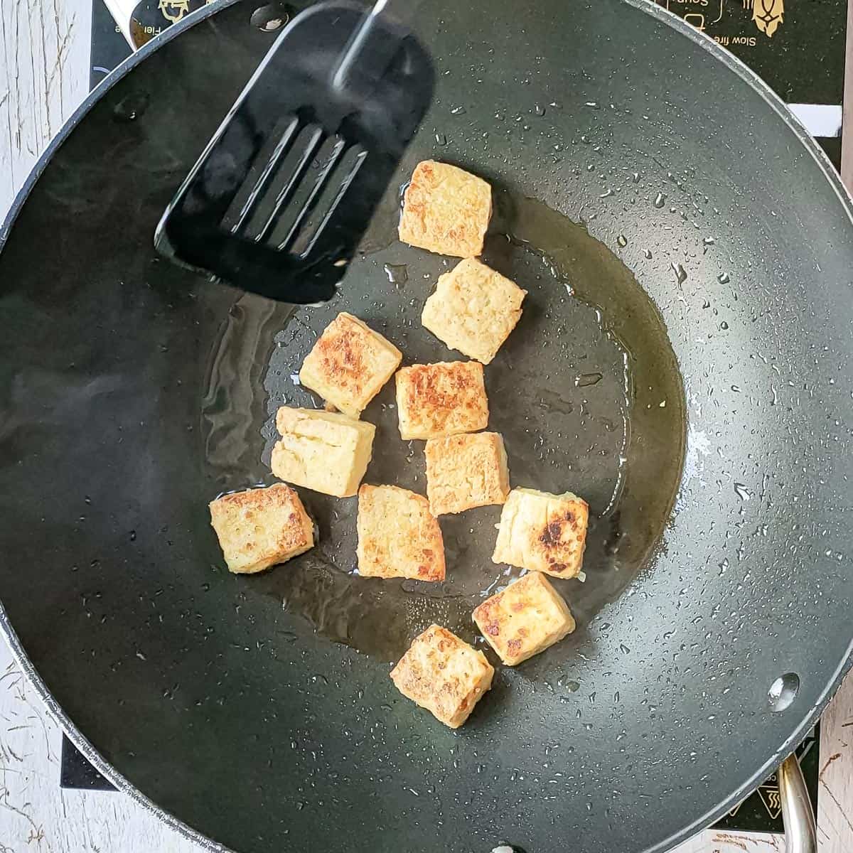 golden brown fried tofu in a wok.