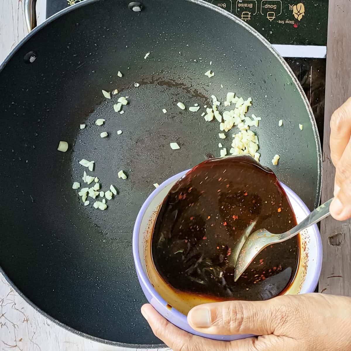 honey garlic sauce being added to stir-fried garlic.
