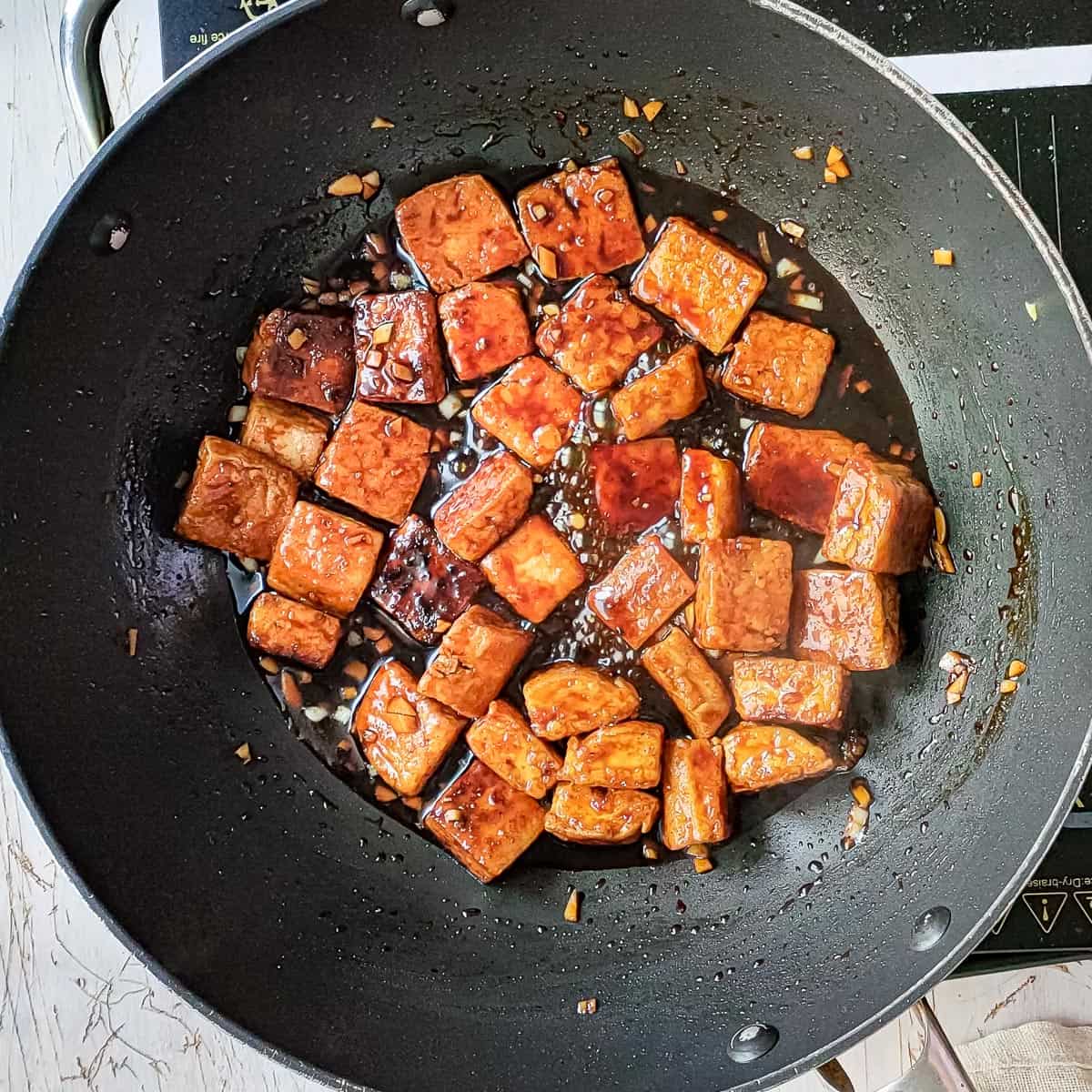 pan fried tofu simmering in honey garlic sauce.
