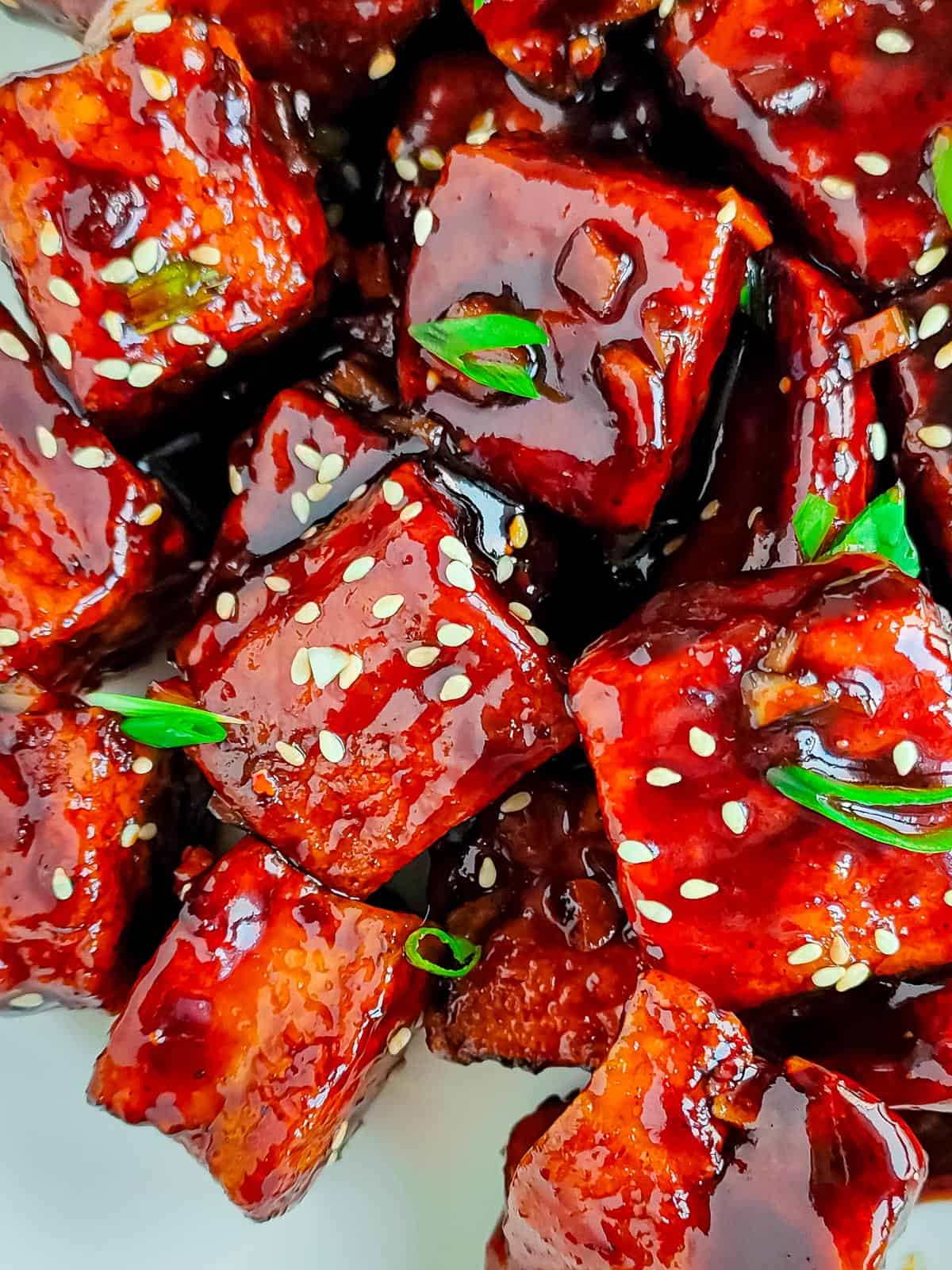 closeup view of sesame garlic tofu on a white plate.