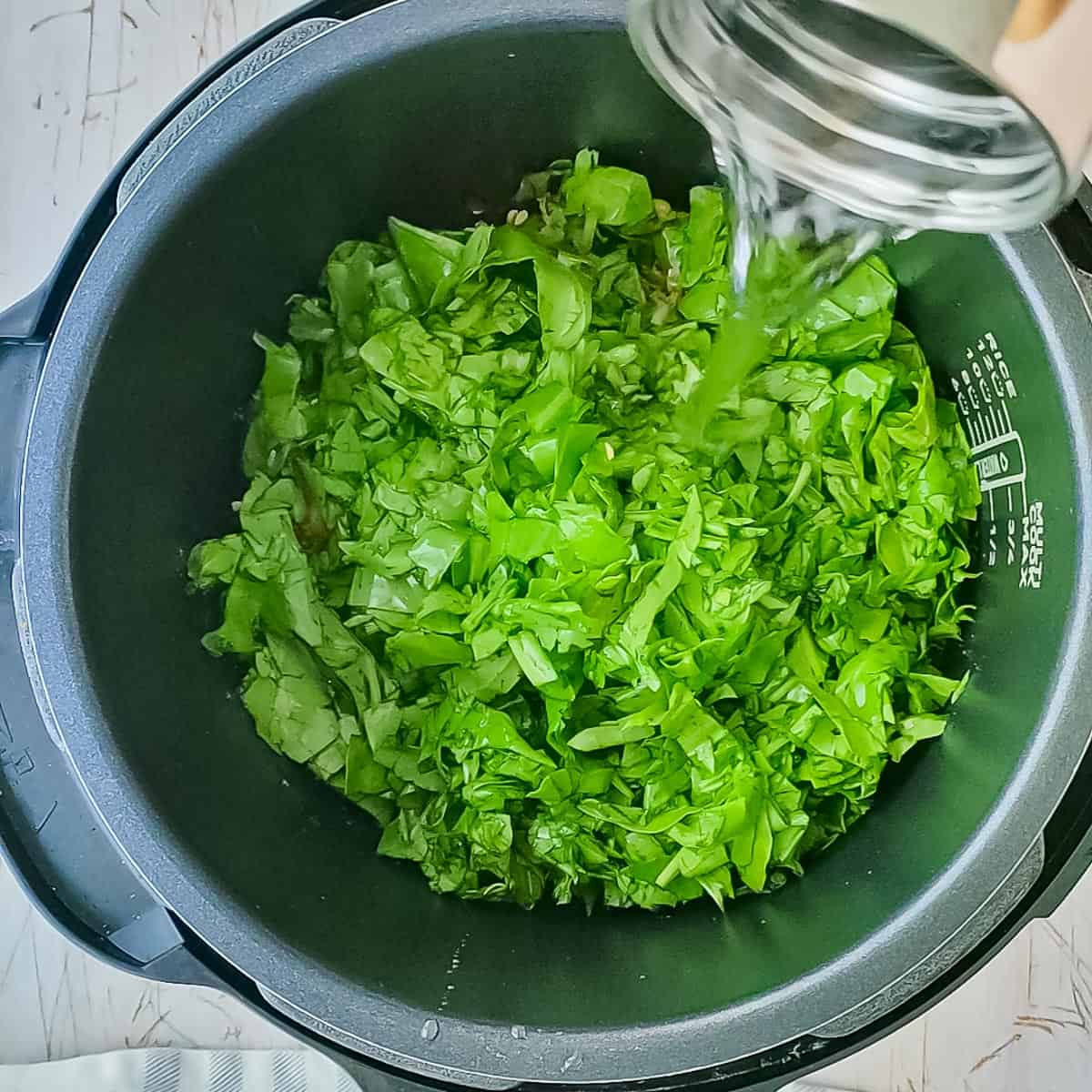 water being added to spinach and dal into the instant pot.