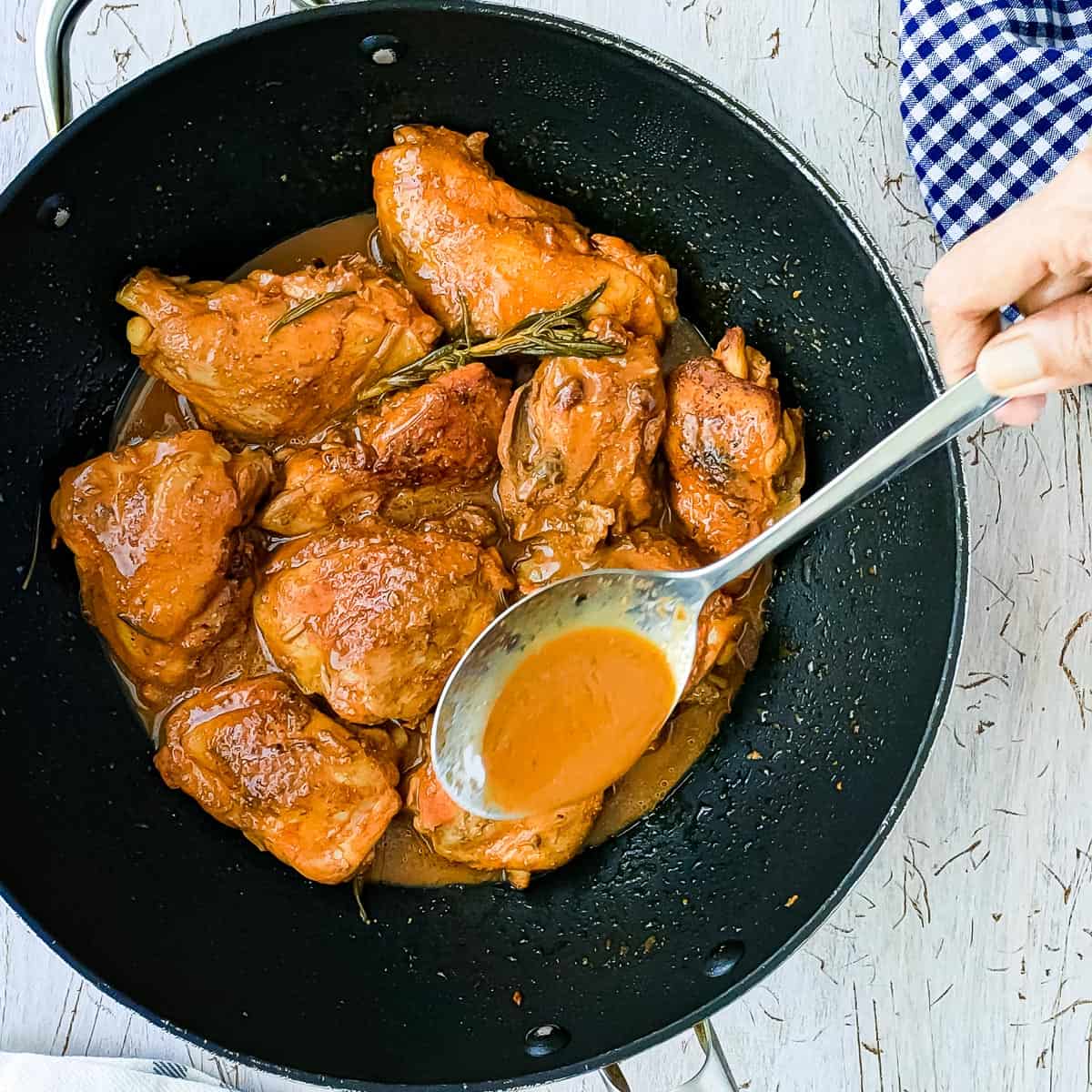 spicy braised balsamic chicken with rosemary sauce in a pan with a spoon.