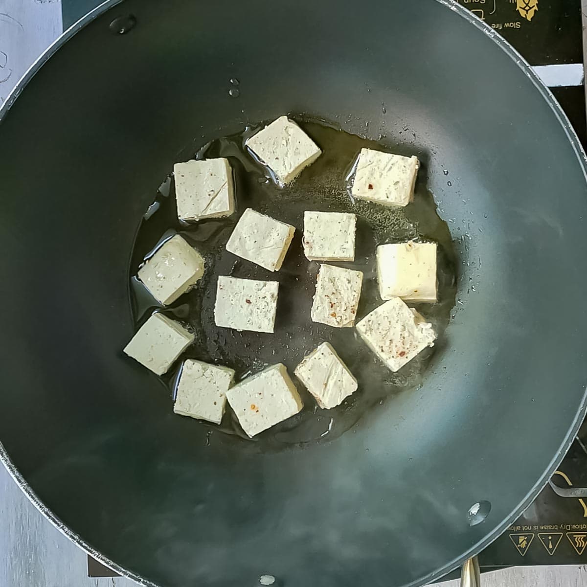 Tofu placed in hot oil in a non stick pan.