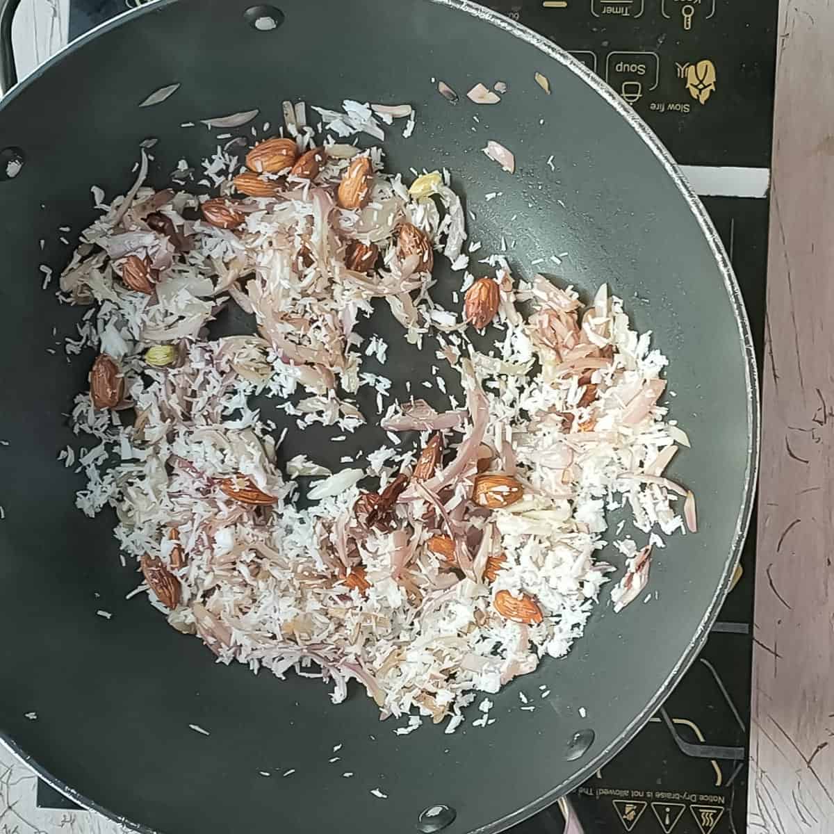 Creamy Chicken Kofta Curry Fried coconut and almonds in a non-stick pan.