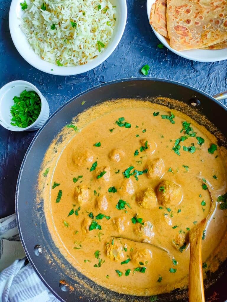 Chicken kofta curry in a non-stick pan with rice and rotis.