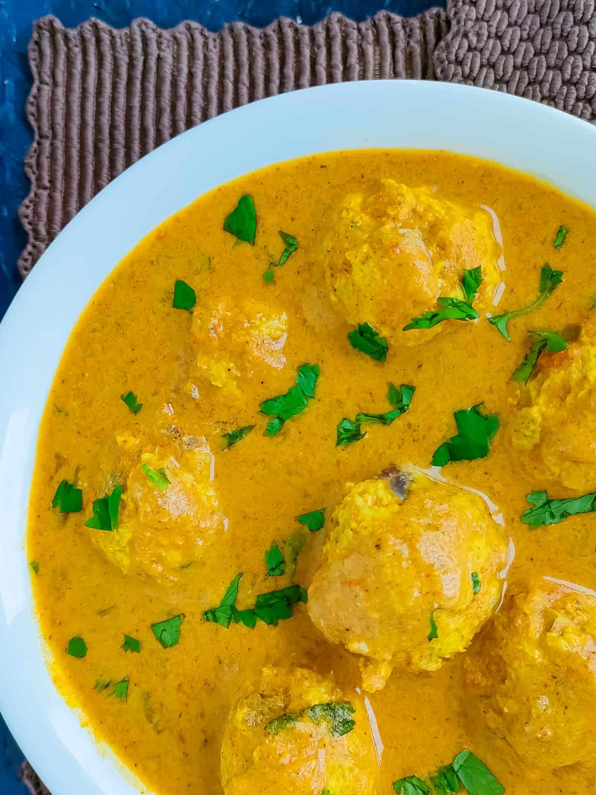 Chicken meatball curry in a white bowl.