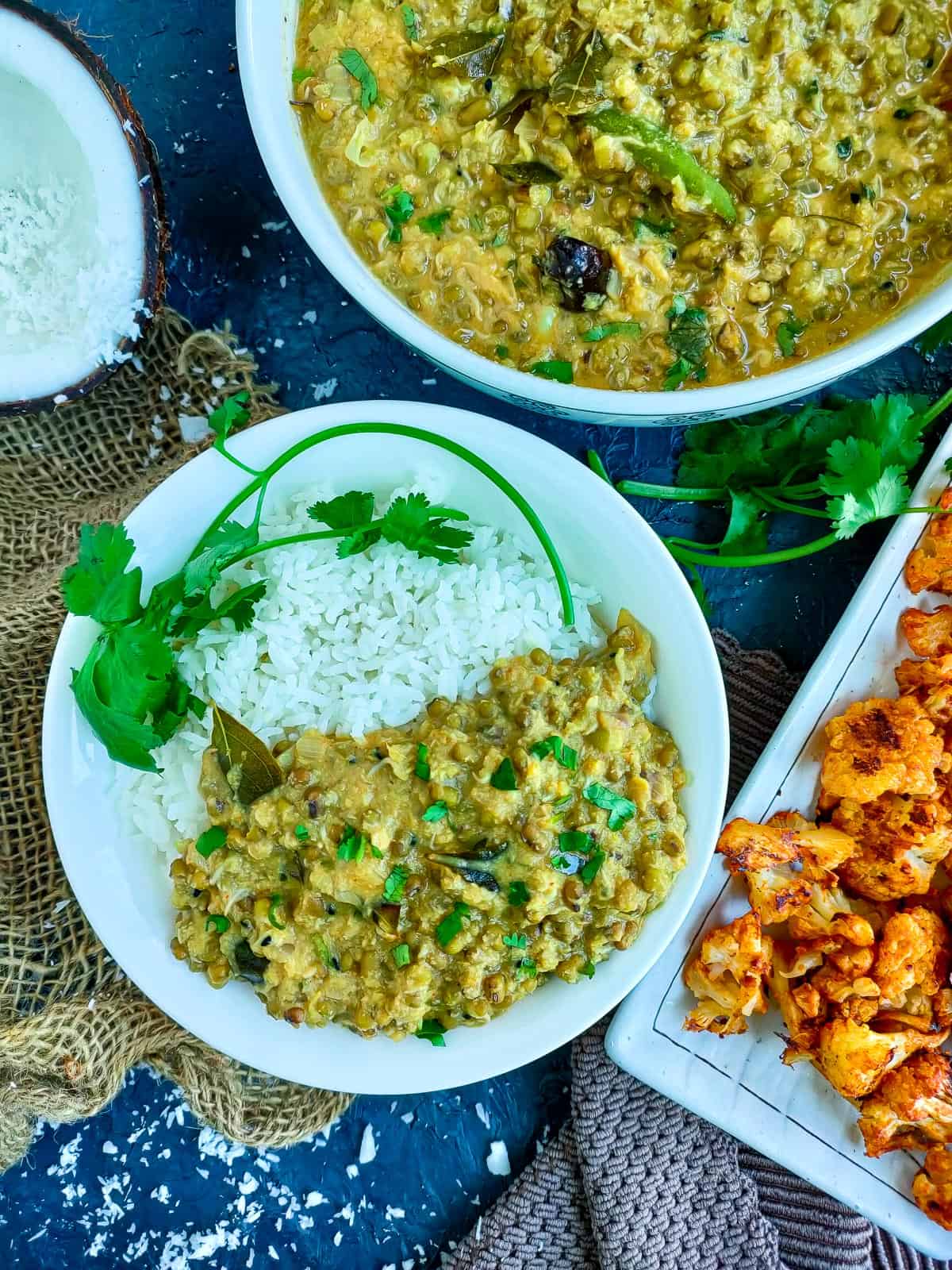 Mung beans curry served with rice on a white plate and a bowl of corry and tandoori cauliflower on a plate.