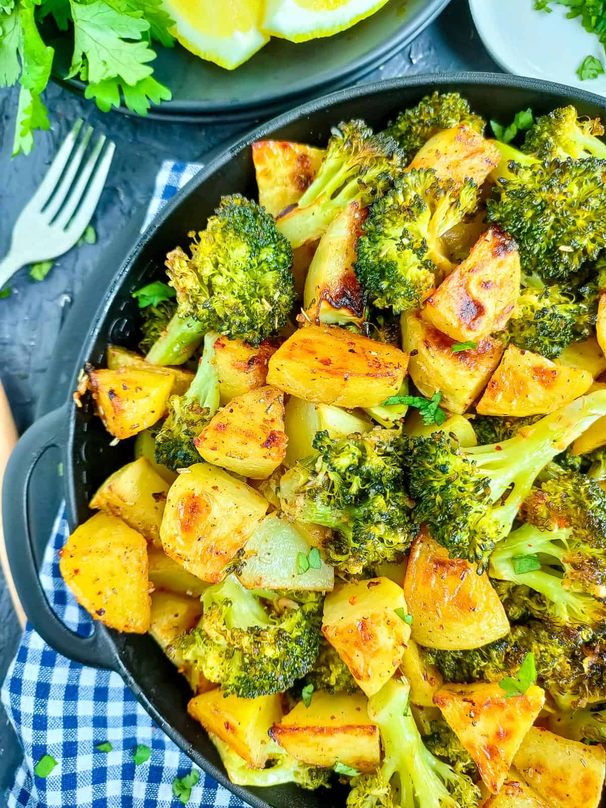 Sheet pan broccoli and potatoes on a black plate.