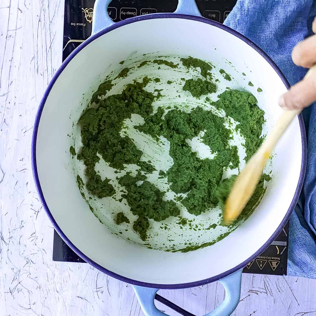 Green curry paste being sauteed in a pot.