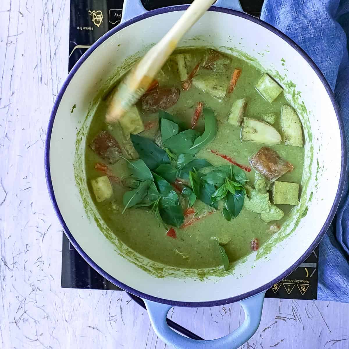 Basil leaves being added to Thai green curry.