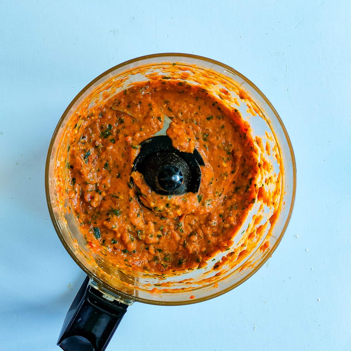 Blended chilli and basil pesto in a food processor jar.