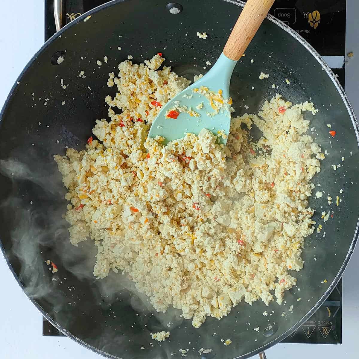 Crumbled tofu being stir fried in a wok.