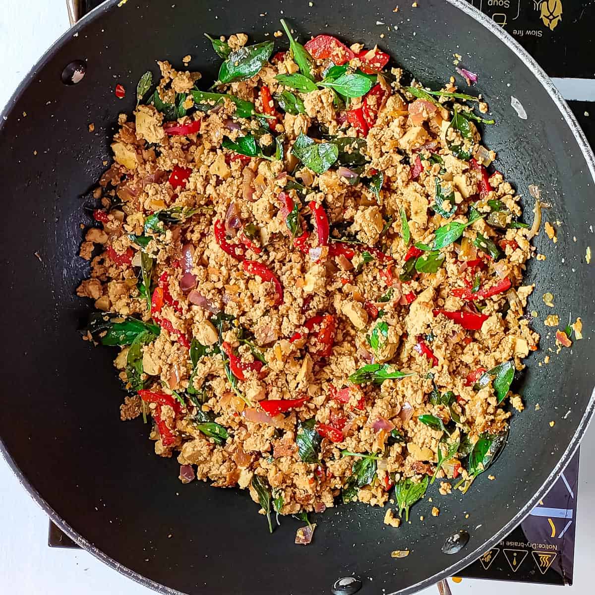 Basil tofu being stir fried in a wok.