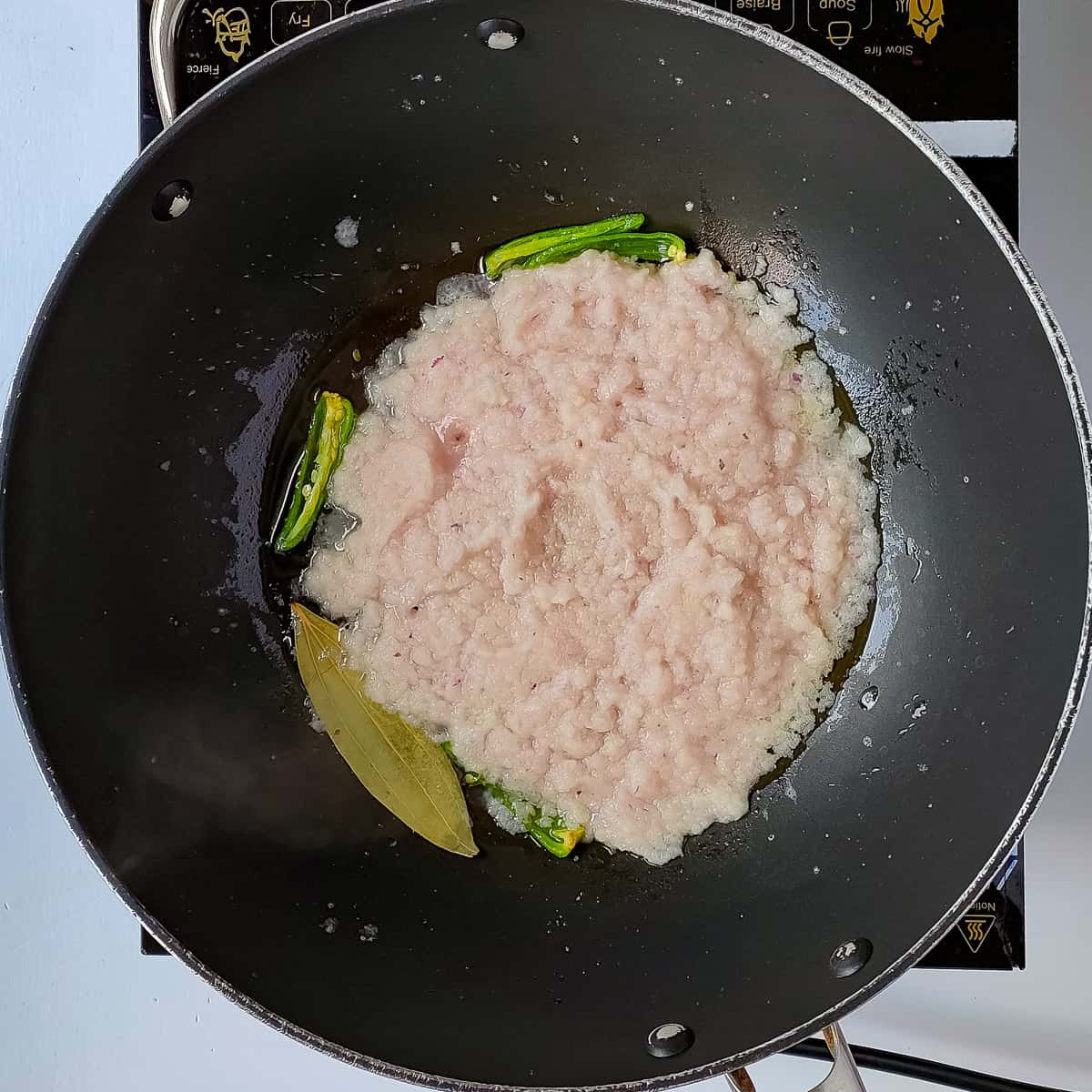 Onion paste being sauteed for pepper chicken masala.