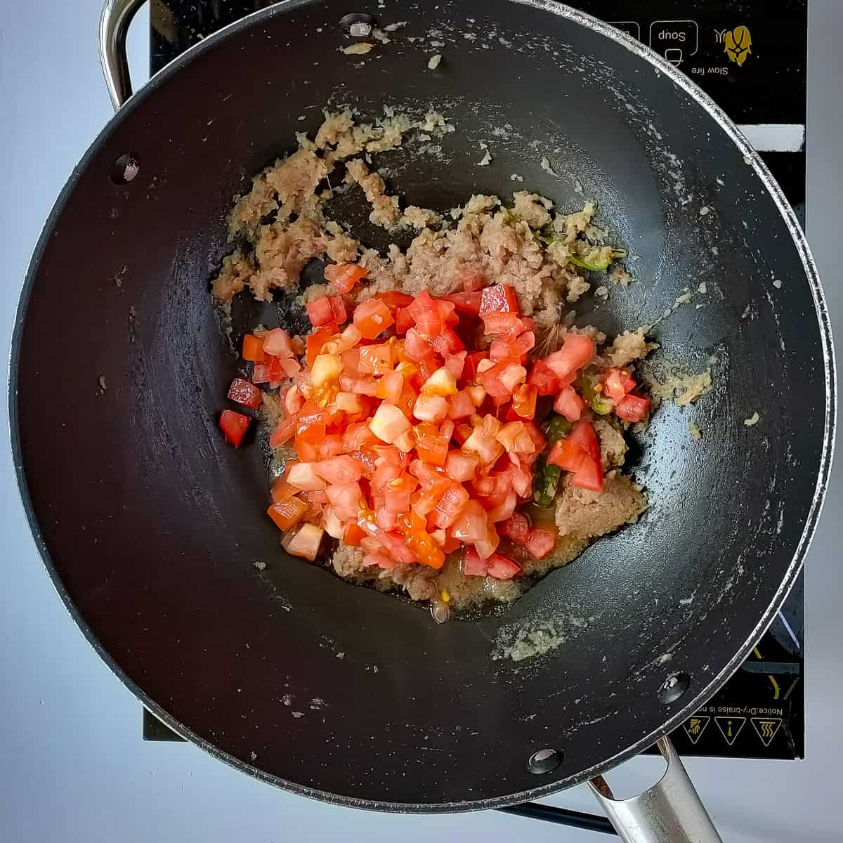Tomatoes being sauteed for chicken pepper masala.